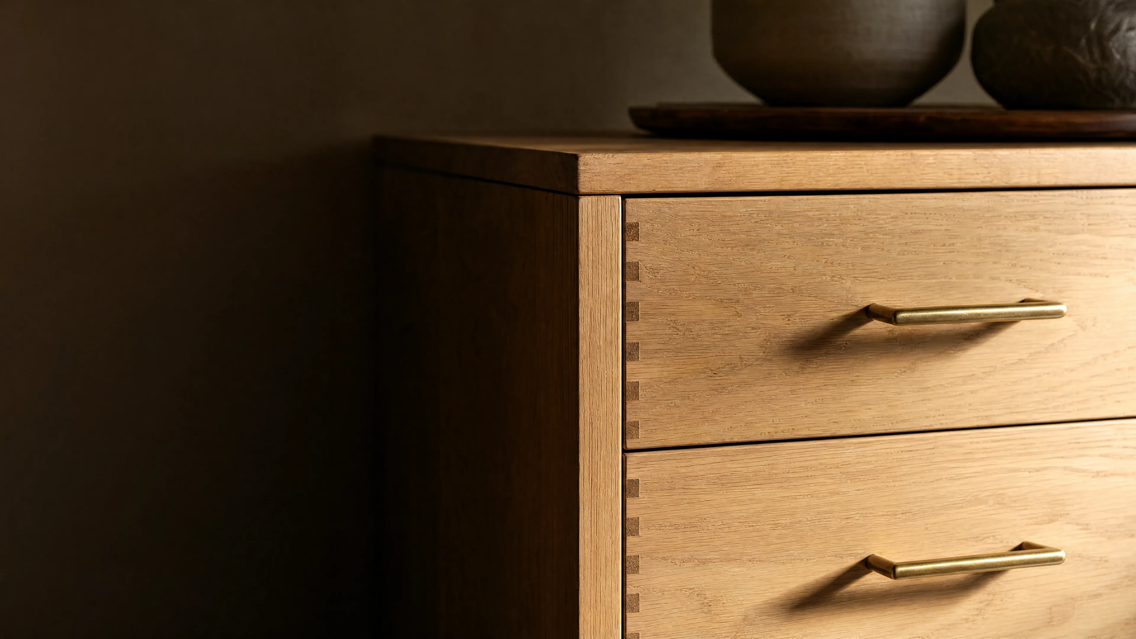 Dovetail joinery and a brass pull on an oak drawer front.